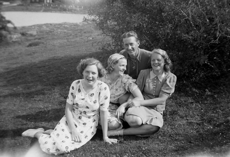 Enligt senare noteringar: "Tre kvinnor och en man sittande på en äng. Johan Börjesson-Eld (?) tillsammans med: Valborg Johansson, Elsa Karlsson och Judith Johansson."
