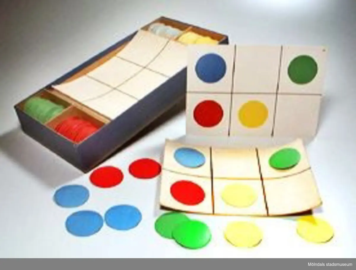 Prickspel. Består av 15 st elevplattor och 30 st lärararplattor. Till hör cirkelplattor i färgerna: rött, grönt, blått och gult (60 st av varje). Plattorna och cirklarna har kardborreliknande tyg, för att fästa mot varandra. Spelet går ut på att läraren visar upp en platta med ett visst mönster (av cirklar i olika färger) för eleverna. De får sedan lägga samma mönster, utan förebild på egna arbetsplattor. Det saknas en röd och en gul cirkelplatta. Spelet förvaras i en gråblå pappkartong. Spelregler i lockets insida.