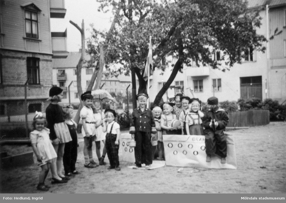 Troligtvis daghem i Guldheden, Göteborg 1945-. Flera barn som står på en lekplats.