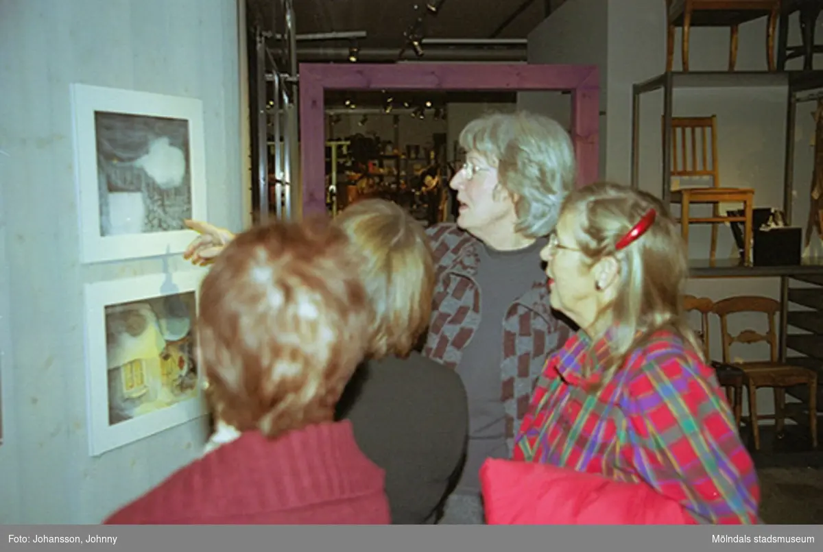 Invigning på Mölndals museum 2002-11-30.
Museichef Mari-Louise Olsson (andra från vänster) tittar på målningar tillsammans med besökare.
Tomteutställningen: 30/11-02 - 1/1-03.