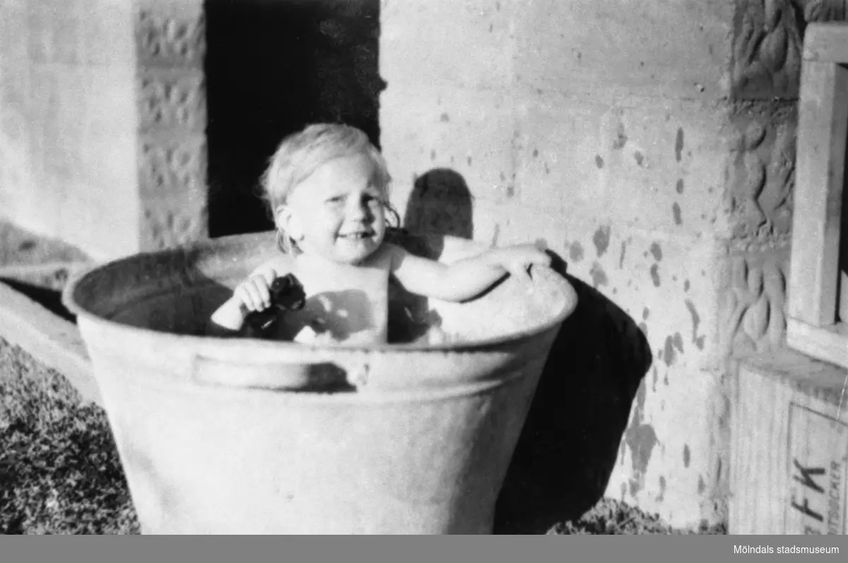 Karin Pettersson (gift Hansson) badar i en zinkbalja utanför bostaden, Gamlehagsvägen i Torrekulla cirka 1948.
