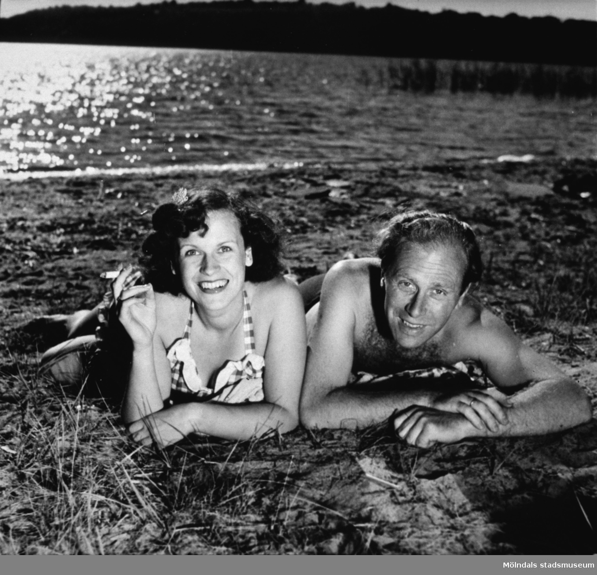 Titti ? med cigarett i handen och Karl-Erik Alberts ligger vid strandkanten, västra Tulebosjön, cirka 1940-tal.
