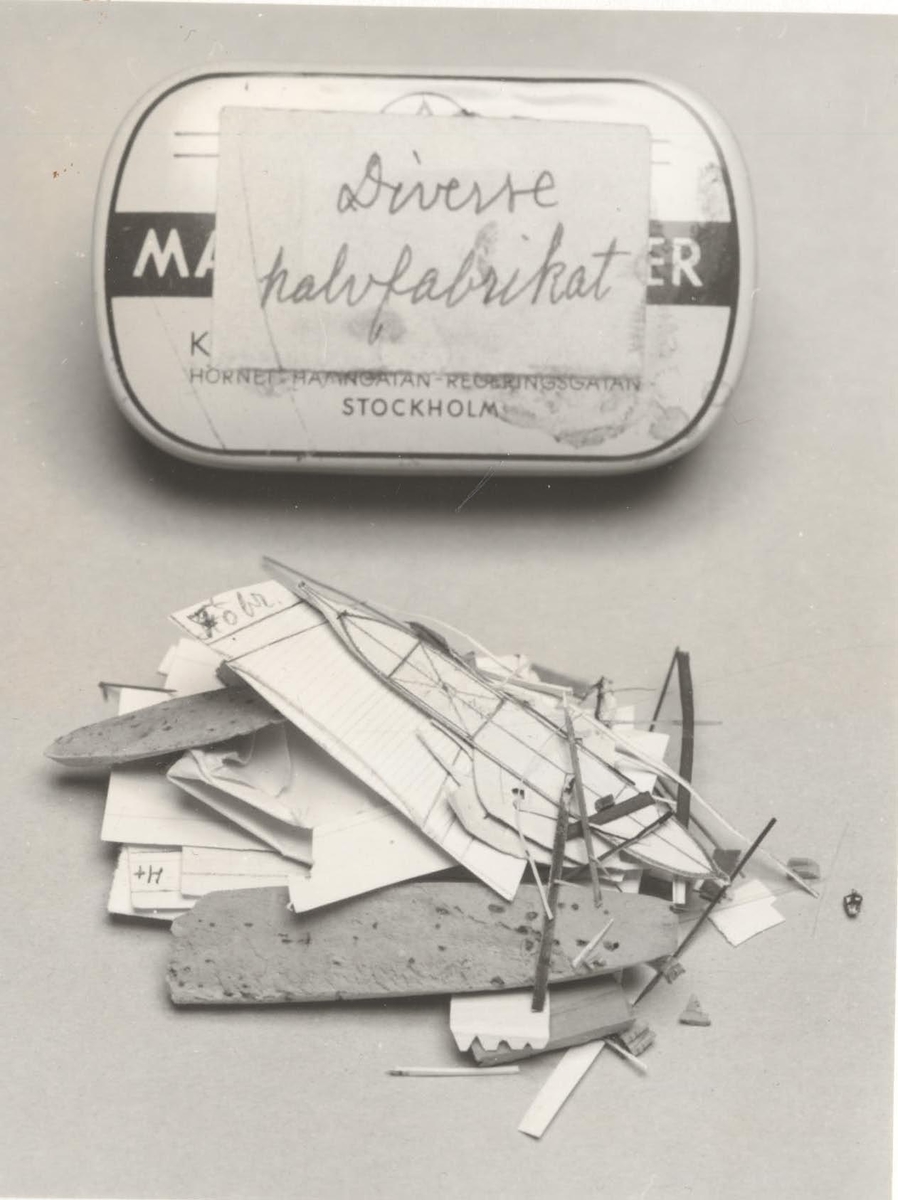 Plåtask märkt "diverse halvfabrikat", innehållandes
pappersbitar och liten båt i kork.
Har tillhört modellbyggare och kapten Patrik De Laval.