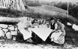 Familiegruppe, seks personer har kaffeselskap i hagen i Syst