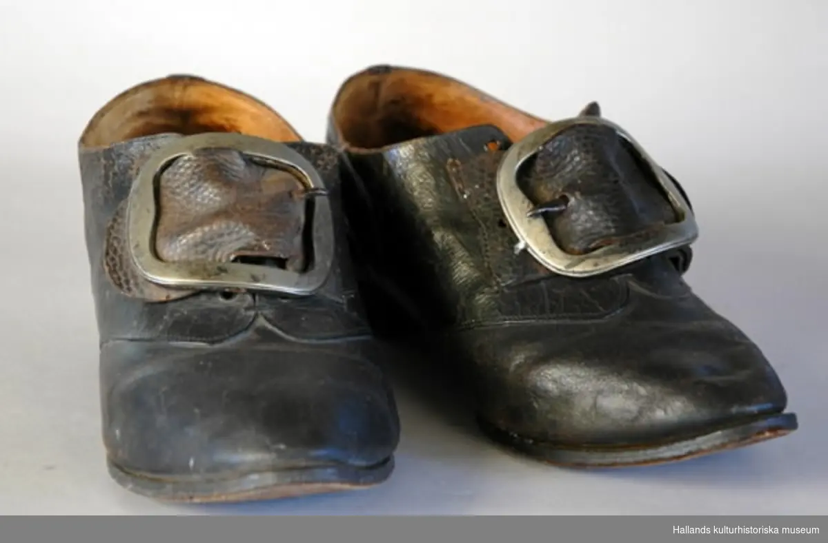 Skor, par, höger och vänster sko lika (så kallade vändeskor). Hål för snörning, spännen av silver.