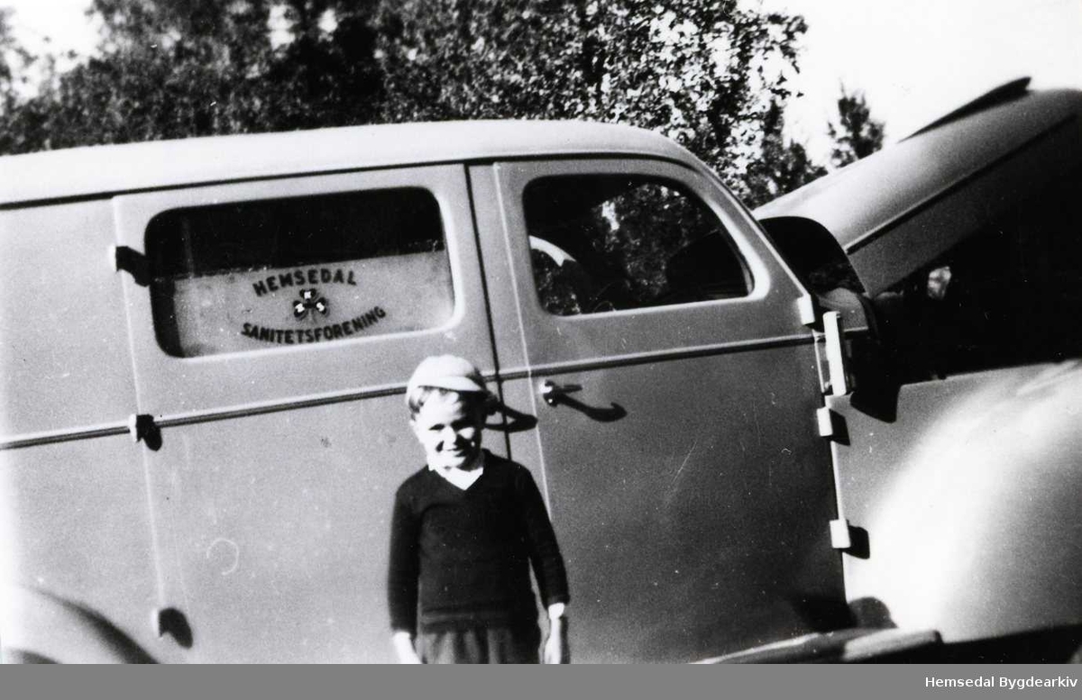 Dette er truleg den fyrste sjukebilen i Hemsedal, ein Dodge 1937 modell, som Hemsedal Sanitetsforening åtte. I 1953 bytta Hemsedal Sanitetsforening namn til Hemsedal Helselag. 
Guten er Per O. Engene.