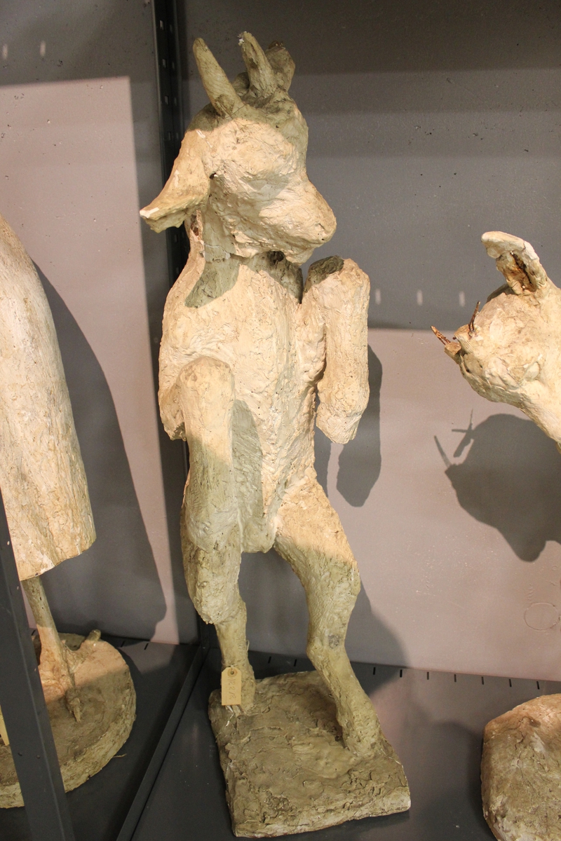 Skulptur i gips av en geitekilling på to bein. Fontenegruppe bl.a. i Flekkefjord. Se også nr.071, nr.075, nr,076, nr.077 og nr.217