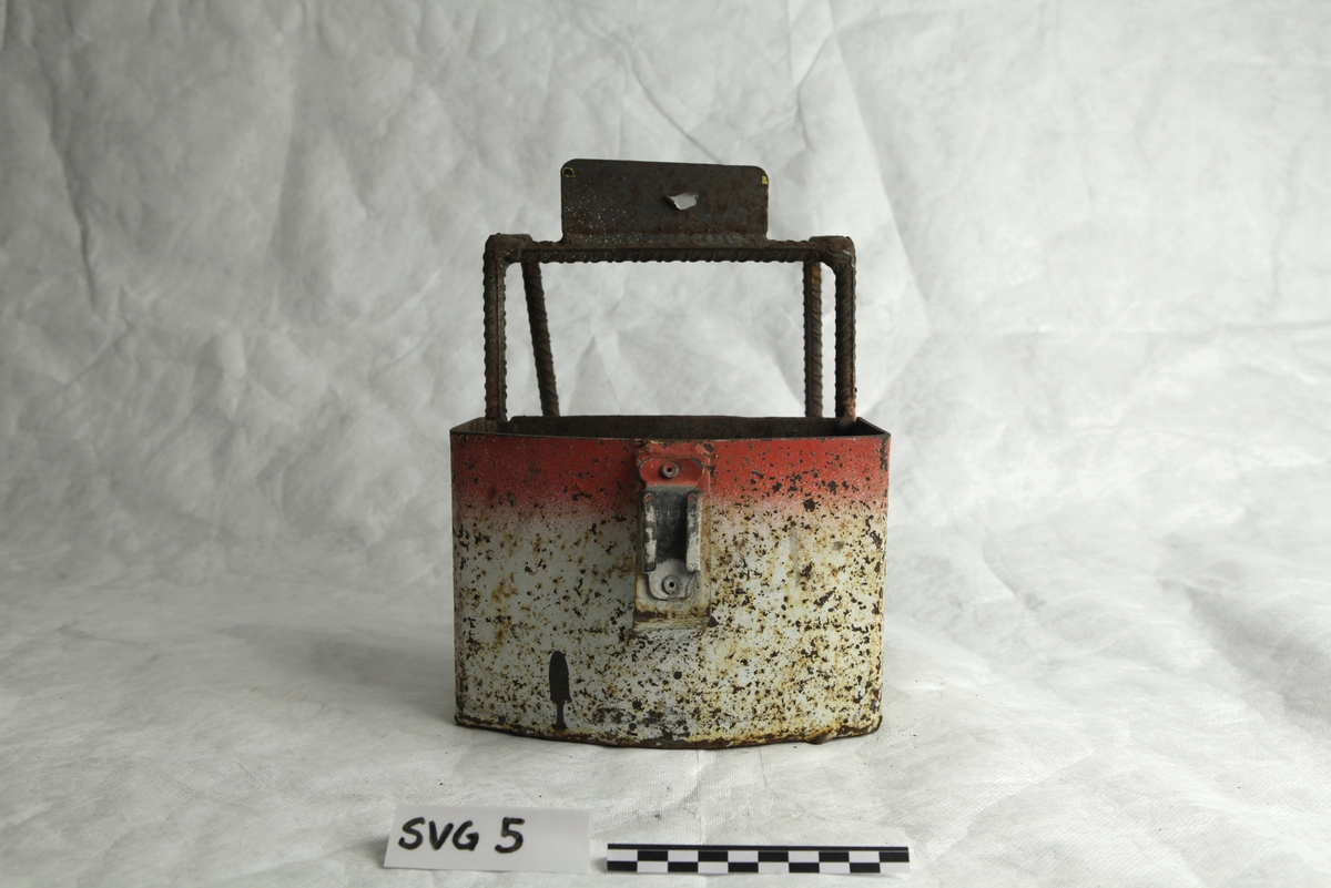 Rød - og hvitmalt liten metallboks med opphengskroker. En del korrosjon kommer gjennom malingslaget.