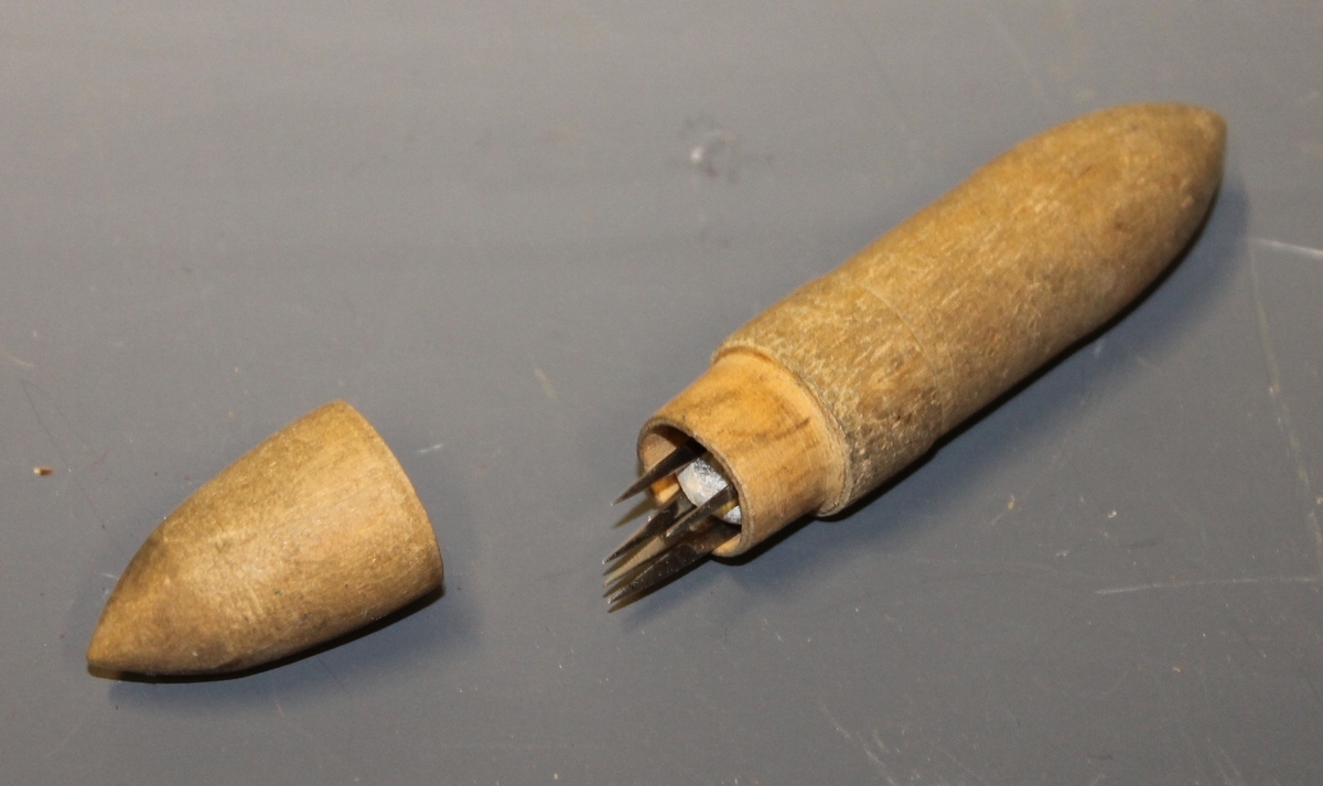 Nåletui med rundt tverrsnitt, etuiet spisser i begge ender og inneholder 8 nåler og kritt.