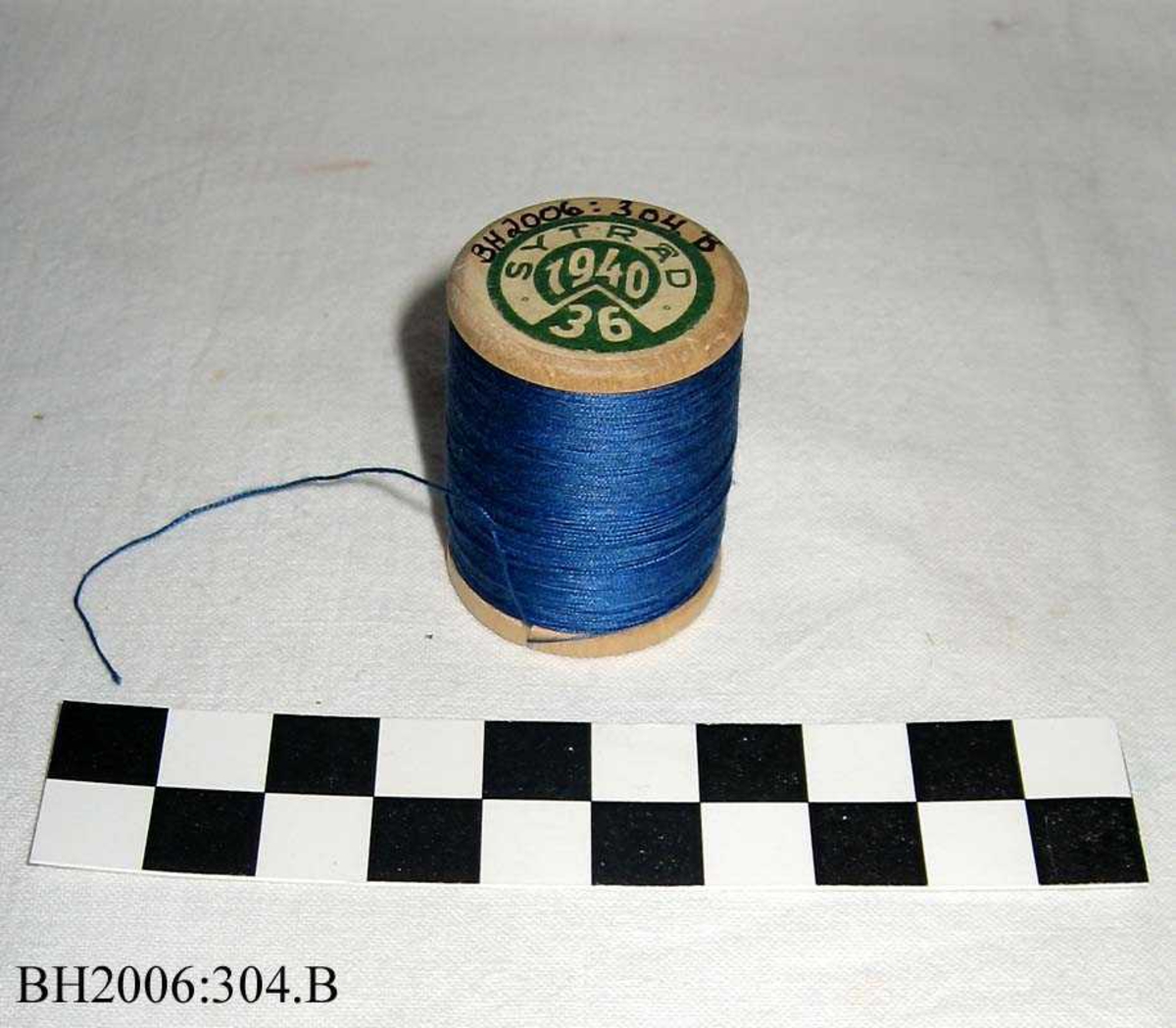 Trådsnelle med blå tråd, og kjerne av tre og etikett i hver ende.