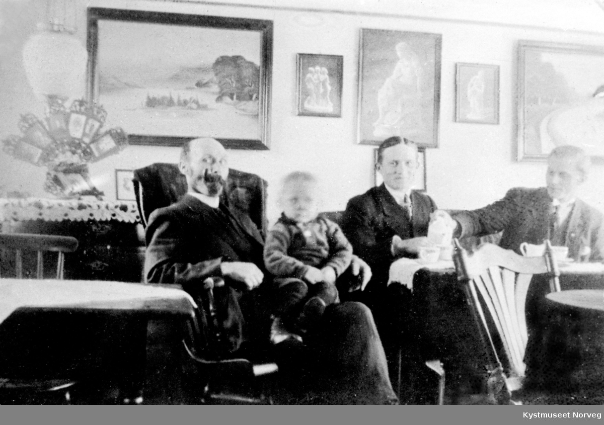 Fra venstre: Isak Jensen og Adolf Hestvik sammen med noen ukjente i en stue