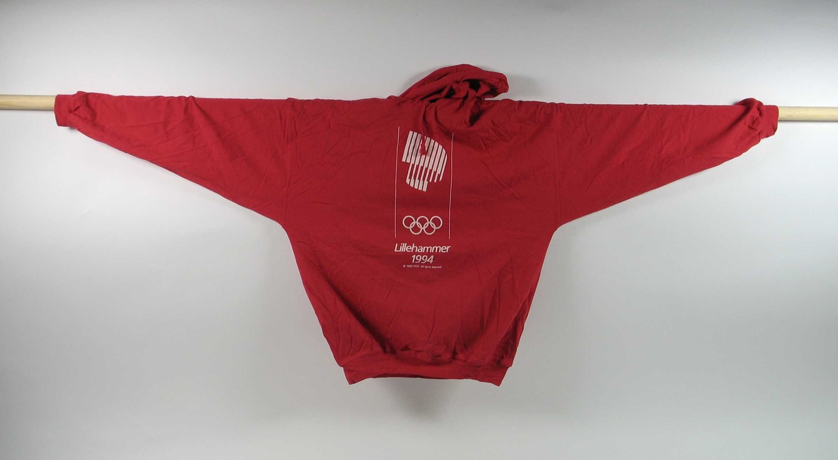 Rød hettegenser med innslag av hvitt i størrelse x-large. Foran på genseren er det en logo for de olympiske vinterleker på Lillehammer i 1994. Snorstramming i halsen for hetten.
