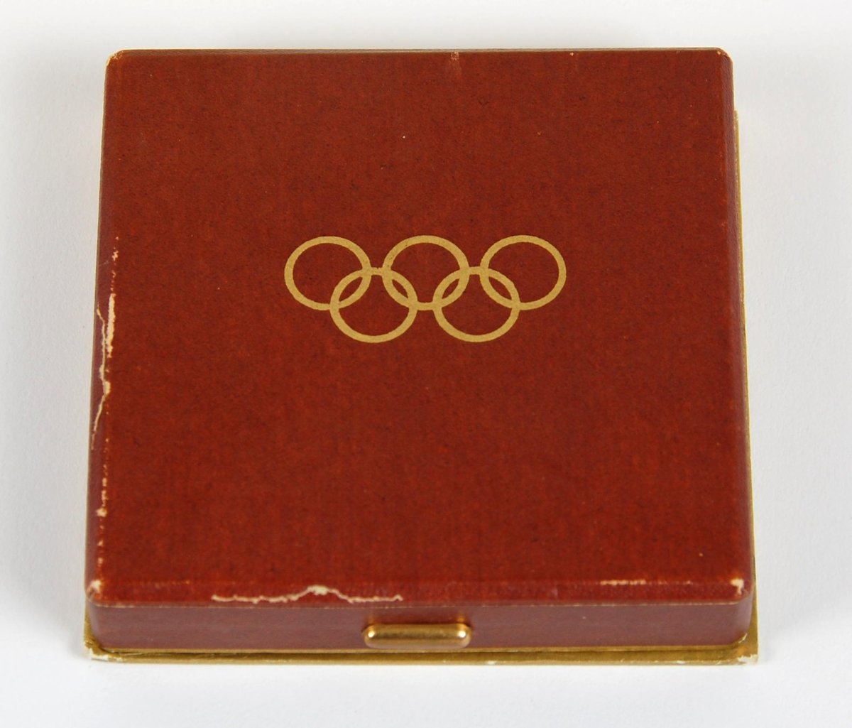 Kobberfarget medalje. På forsiden finner man emblemet til vinterlekene i 1952, som består av en siluett av Oslo rådhus og de olympiske ringer. På baksiden finner man det olympiske motto; citius - altius - fortius sammen med tre stiliserte snøkrystaller. Medaljen ligger i et brunt etui av papp med gullfargede olympiske ringer  på lokket