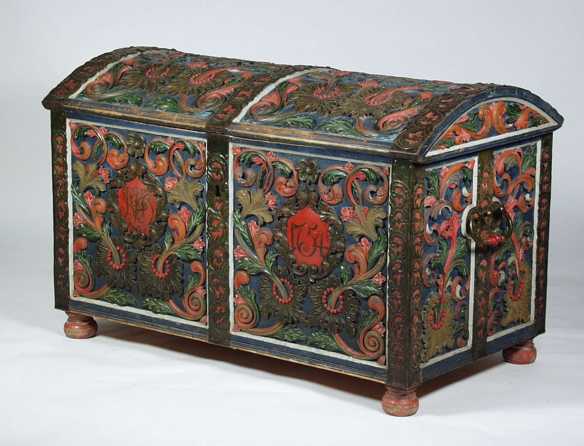 En kiste i furu med akantusskurd og er malt i blå bunnfarge. Kisten har også jernbeslag med uthamret ranker på hver kant og på midten av kisten. På fronten av kisten blir innskriften rammet inn av akantuskranser.