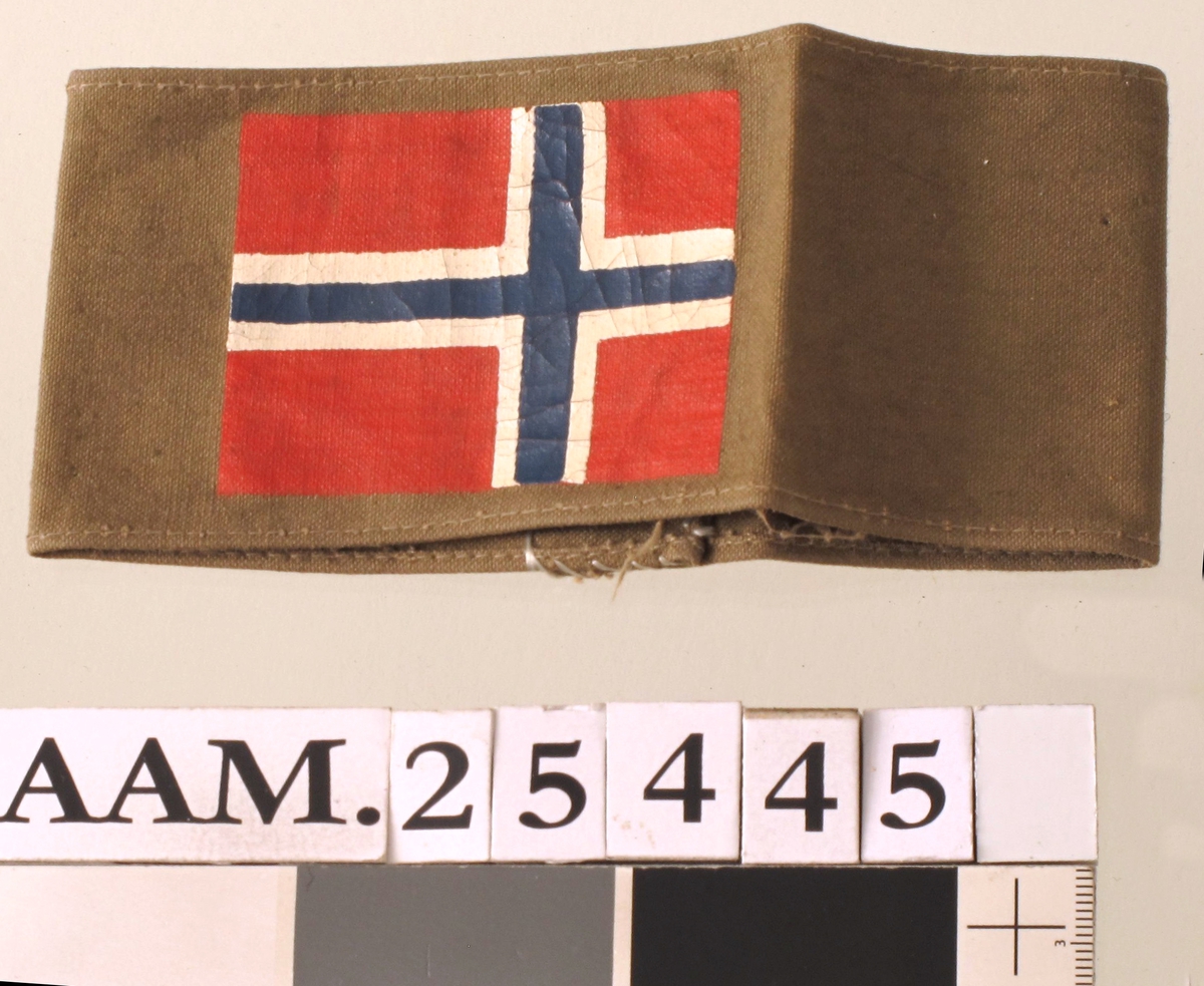Bånd i jordgrønn farge, med påmalt norsk flagg.