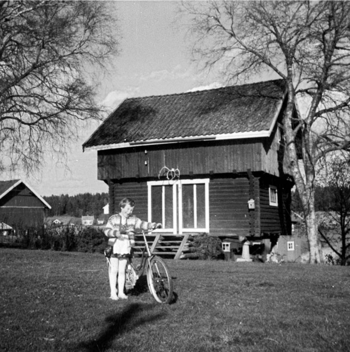 Jente med sykkel på tunet til Søgar'n Kjustad. Bua bygget 1941.