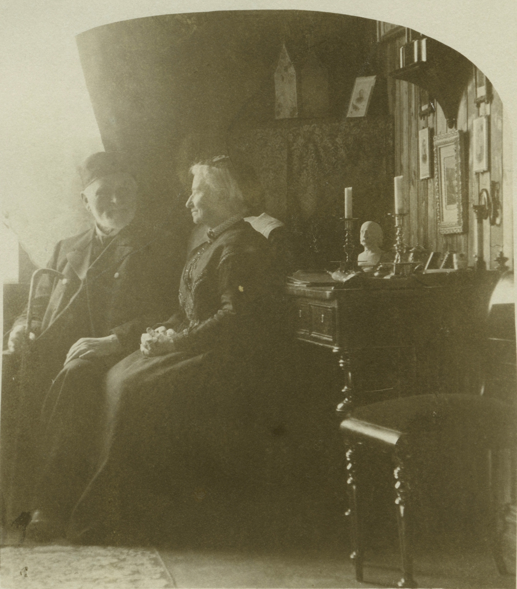 Eldre mann og kvinne sitter foran et skrivebord