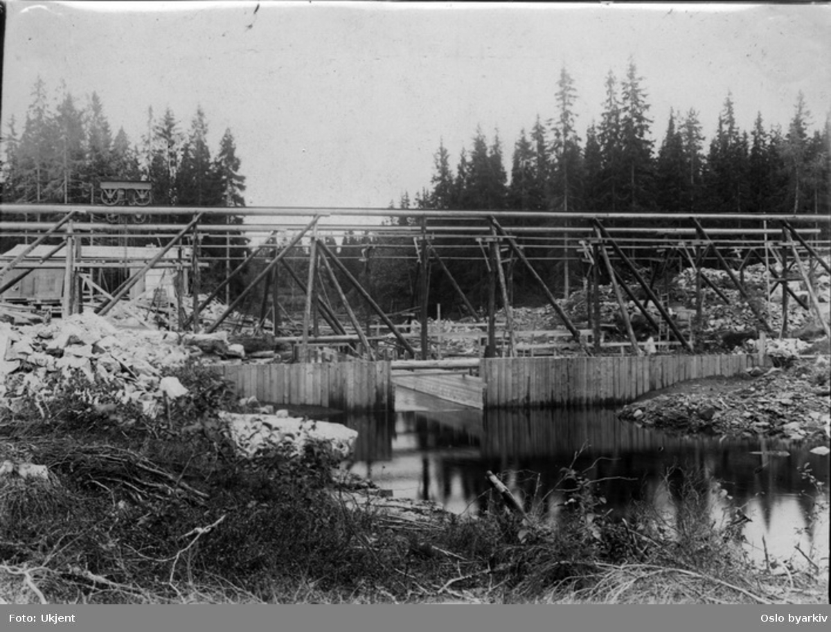 Byggingen av den nye Øyungsdammen (ferdig 1916). Reisverk i tre. Løfteinnretning med skinnegående tralle øverst. Avløpsrenne.