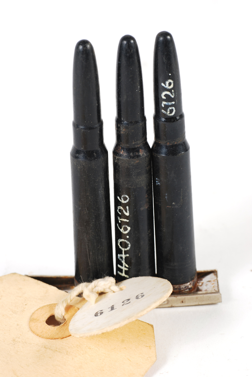 tre ekserserpatroner i sort plast i en ladeklips for mausergevær.