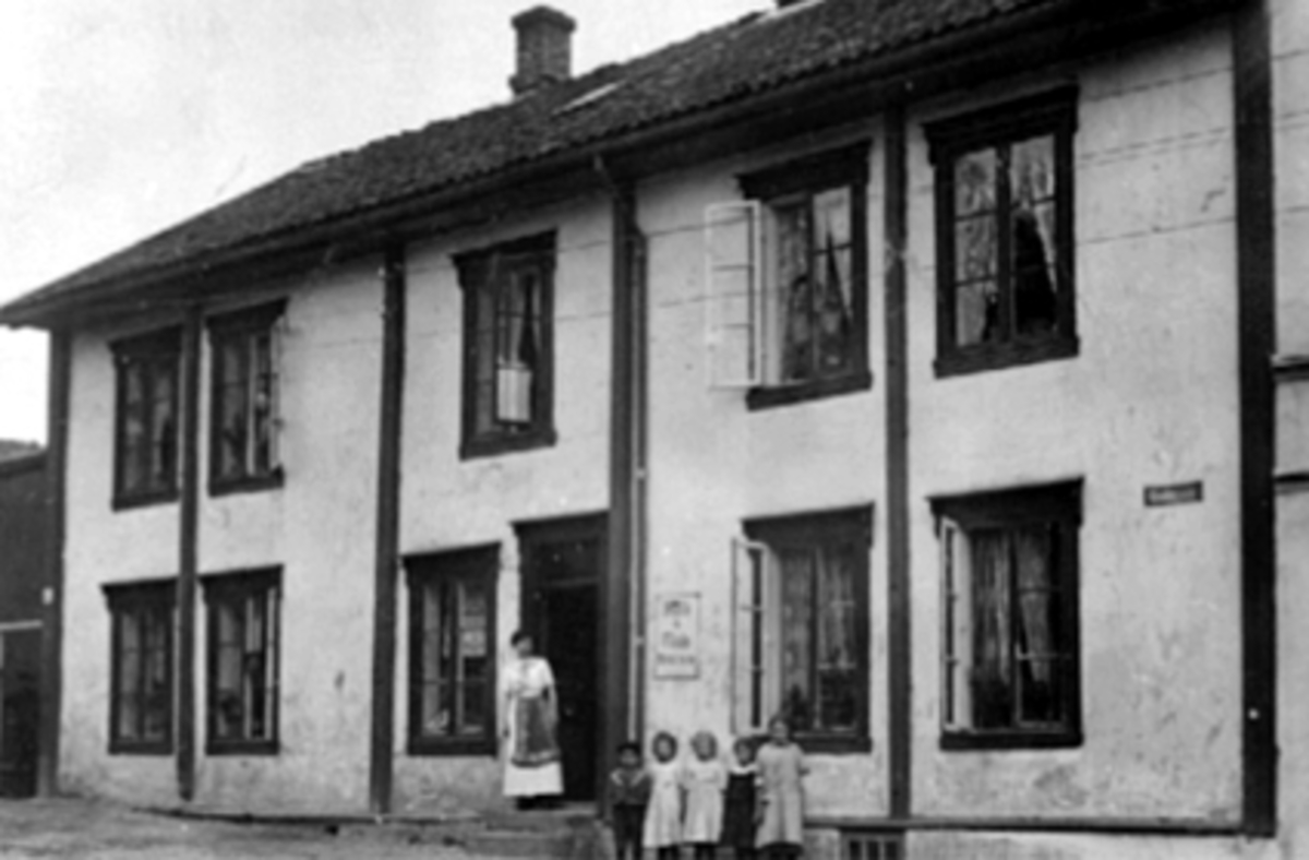 Eksteriør, Vestbyen kolonial, folk. 
Foran huset fra v: Thora Rønning (f. Kirkeby), O. G. Evensen (f. 26. 9. 1906), Asbjørg Hagen (f. Nilsen 16. 6. 1905), Lucie Jølstad (f. Nilsen 26. 1. 1904), Dagmar Kartomten (f. Gundersen 29. 4. 1906), Gudrun Monsen (f. 30. 3. 1903). 
Se En innlandsby vokser fram. bilde nr. 115