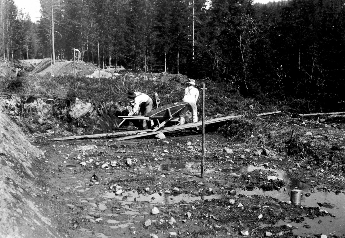 Utgraving av tilførselkanal til Moelv kraftstasjon, ble bygget for Moelv Cellulosefabrikk ca. 1907-1909. Kanalen var 1600 meter lang og kraftverket produserte ca. 800kw. Arbeidere med trillebår.
