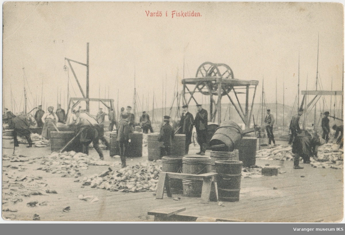 Postkort, fiskearbeid på en av Brodtkorbs kaier i Nordre Våg, Reinøya i bakgrunnen, ca. 1900