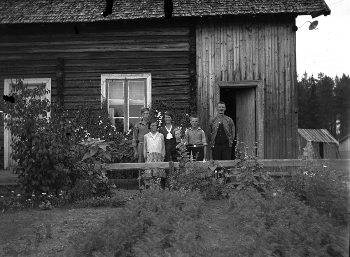 Ukjent familie står foran et hus. 