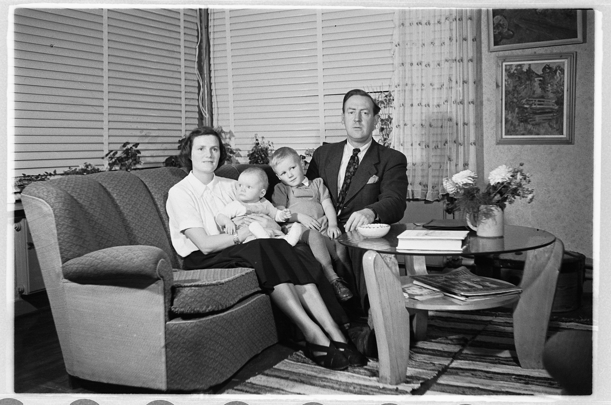 Interiør, stue. Kvinne og mann i en sofa med en baby og en gutt. 