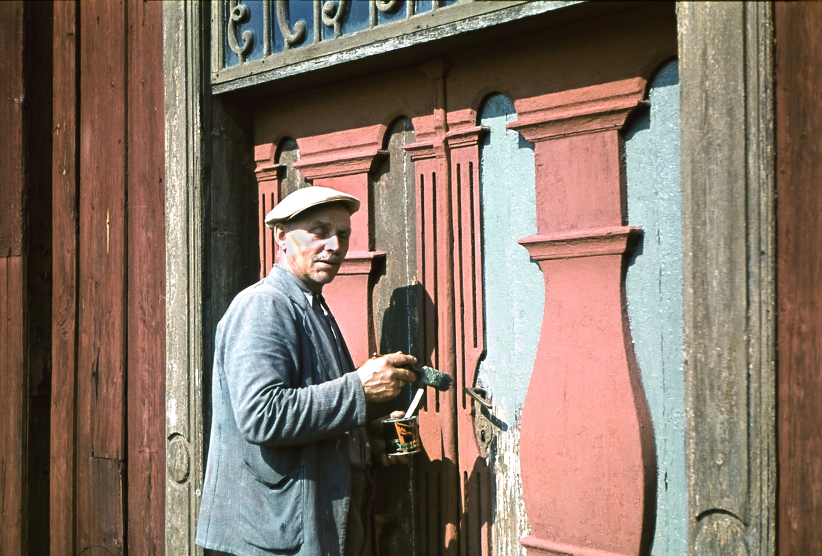 Vaktmester Hans Sanden på Hedmarksmuseet maler hoveddøra til Løtenbygningen i 1950 årene. 