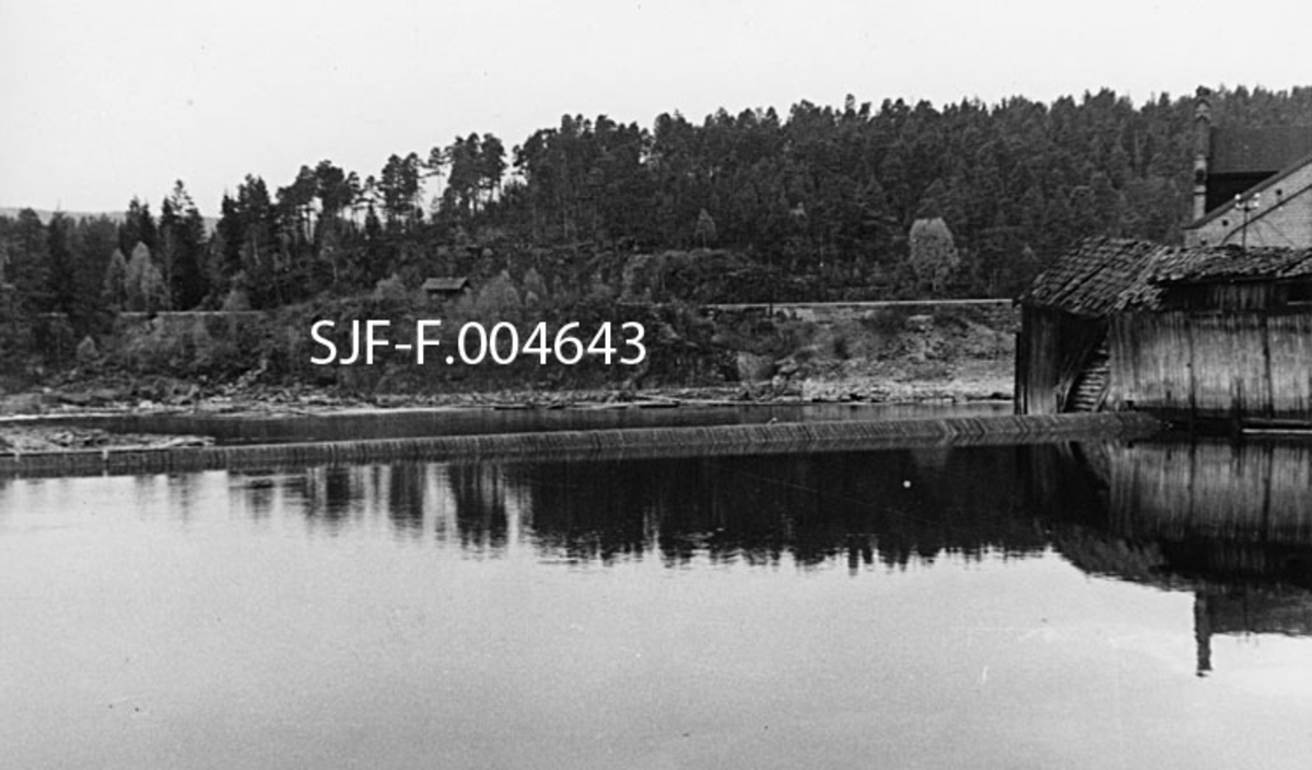 Geithusfossen på Modum i Buskerud, slik den så ut 21. oktober 1945, på et tidspunkt da vannføringa i Drammenselva var ekstremt lav (33 kubikkmeter per sekund).  Fotografiet er tatt i medstrøms retning (akkurat her renner elva nordover) mot terskelen som var bygd like ovenfor det øverste fallet i fossen.  Til høyre ser vi noen forfalne trebygninger.  Bakenfor skimter vi også noe av taket på sliperibygningen, som da dette fotografiet ble tatt fortsatt leverte tremasse til Drammenselvens Papirfabrikker på motsatt side av elva.  Nedenfor aner vi et mer stilleflytende parti (Bronsevja) og Hovtvetåsen med traséen for Randsjordbanen i bakgrunnen. 
