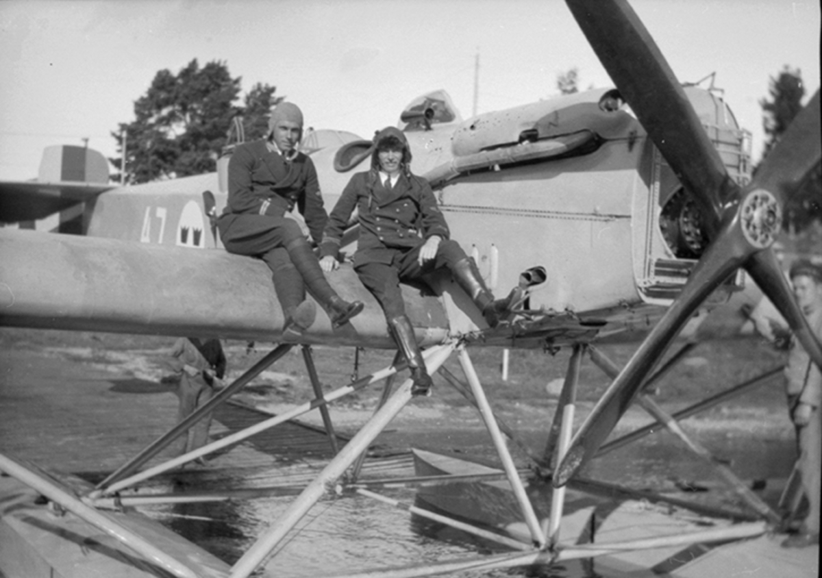 Två flygare ur Flygvapnet sitter på vingen på flygplan Heinkel HE 4 - S 4