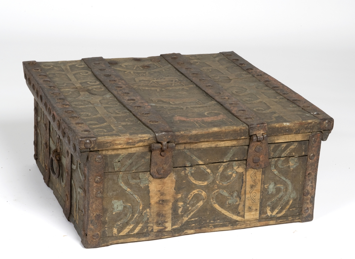 Skrin med flat lokk, jernbeslag og utskåret dekor med plante- og dyrmotiv.