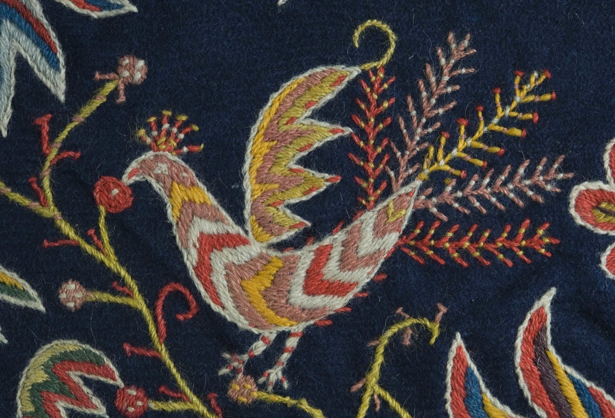Mørkblå putetrekk med brodert dekor i ull, blomster og fugler.