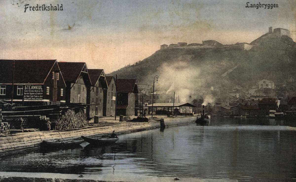 Postkort. Havneområde. Langbrygga i Fredrikshald, nå Halden, med Fredriksten festningen i bakgrunn. Stemplet 1906.