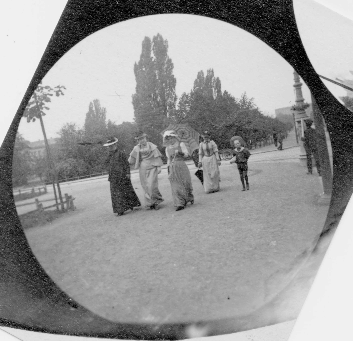 Fire kvinner og et barn på Karl Johans gate, Oslo, mot Slottsparken. Fra venstre: fru Faye Hansen, frk. Salicath, frk Faye Hansen senior.