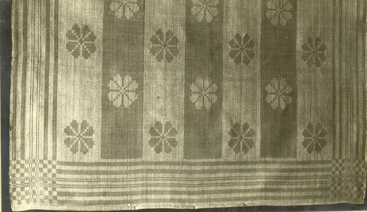 Detalj av hvit serviett i dreiel med rosettmønster og stripebord. Nes verk, første halvdel av 1800-tallet.