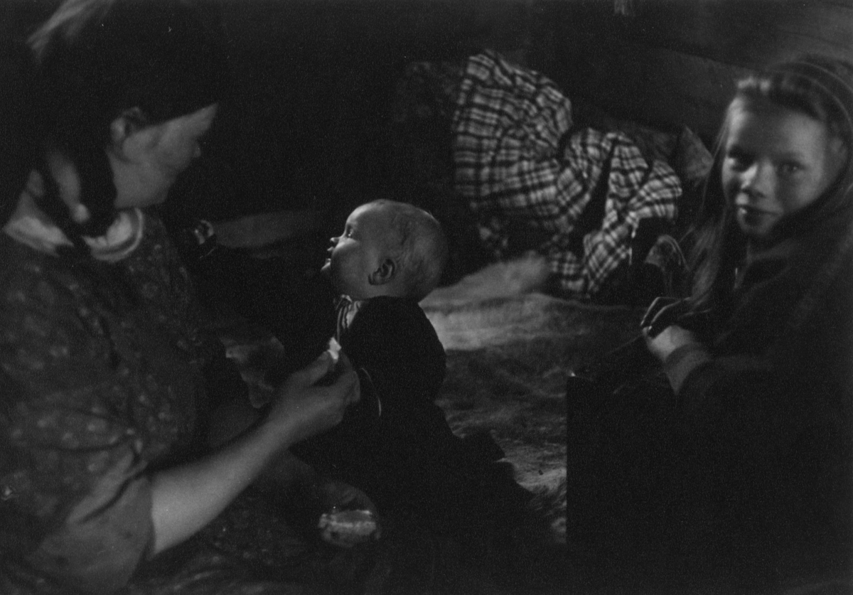 Kautokeinofamilie, en kvinne og to barn i et rom. Kautokeino 1957.