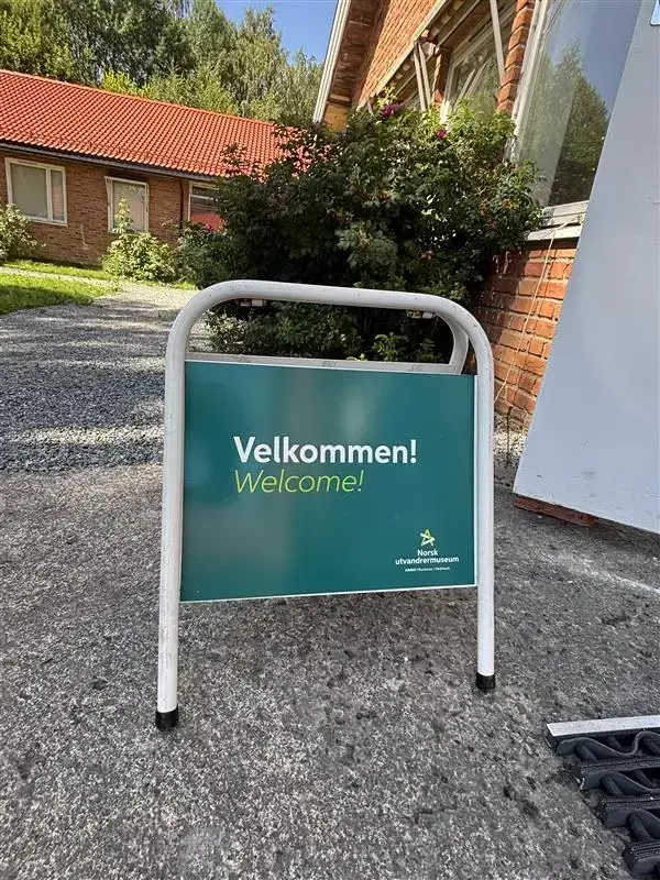 Turkisblått velkommen skilt utenfor murbygning.